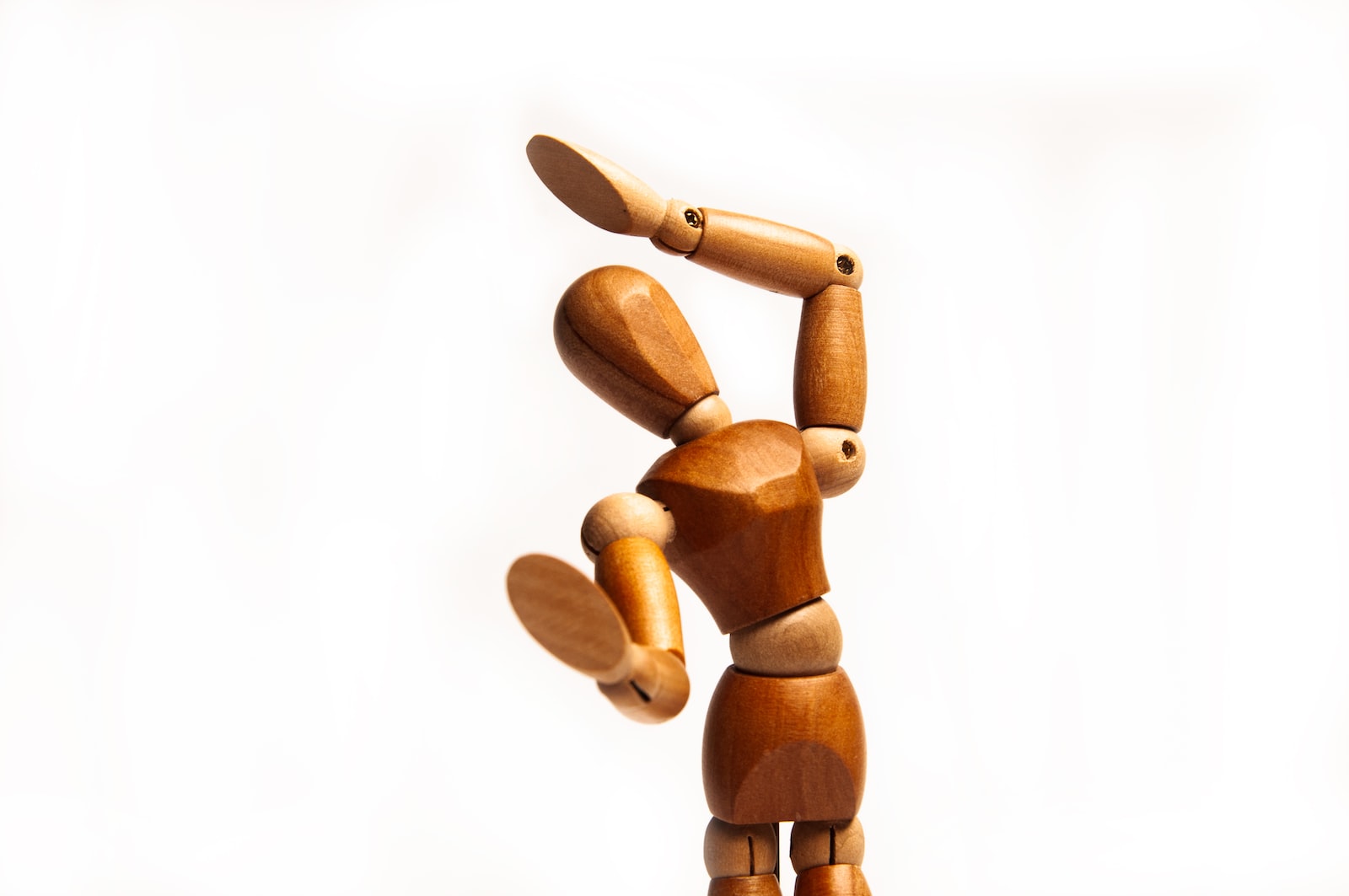 A wooden figurine man with his hands in the air.